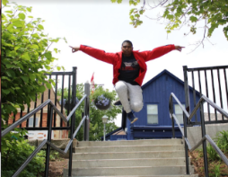 student shown jumping in front of steps with arms outstretched