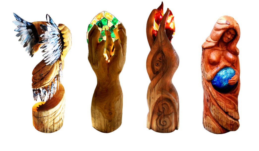 four tall wooden carvings with glass elements. The first has glass wings, the second shows cupped hands holding green and yellow glass elements. The third holds red glass flames, the last is a wooden carving of a woman with a blue glass stomach