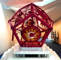 red 3D pentagon art installation on top of a white stair pedestal