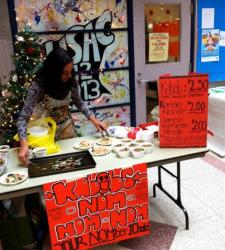Students behind a desk at a food sale competition