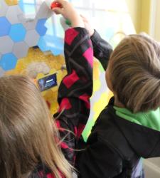 Two kids interacting with a honeycomb.